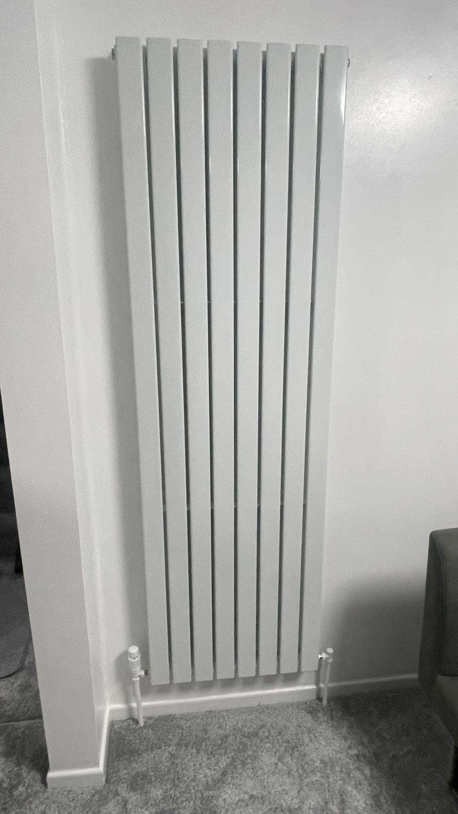 Finished white vertical designer radiator fitted flush against wall in Walsall home