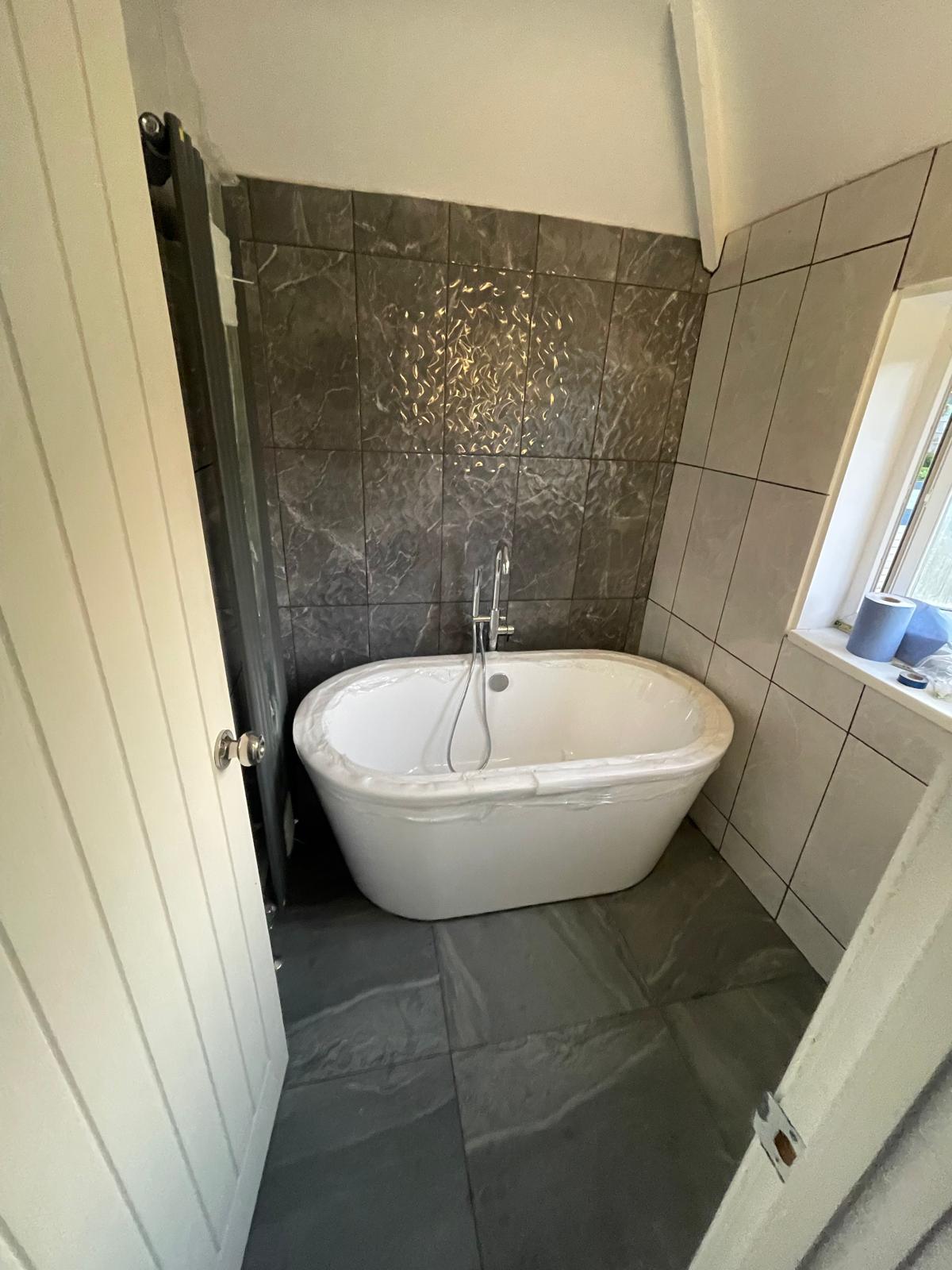 Freestanding bath with dark marble feature wall and chrome taps in Wednesbury bathroom